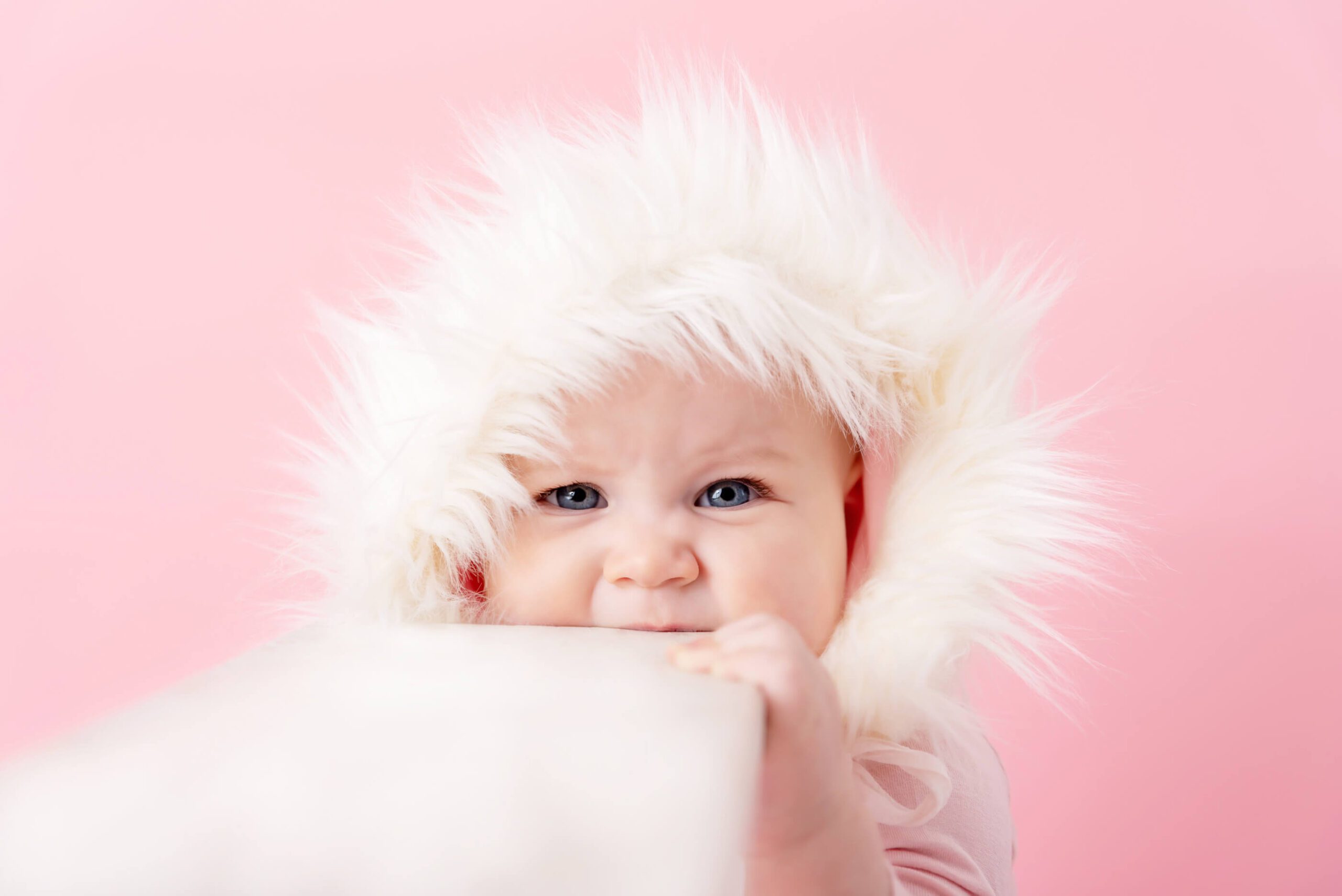 baby girl bitting a ladder with pink background