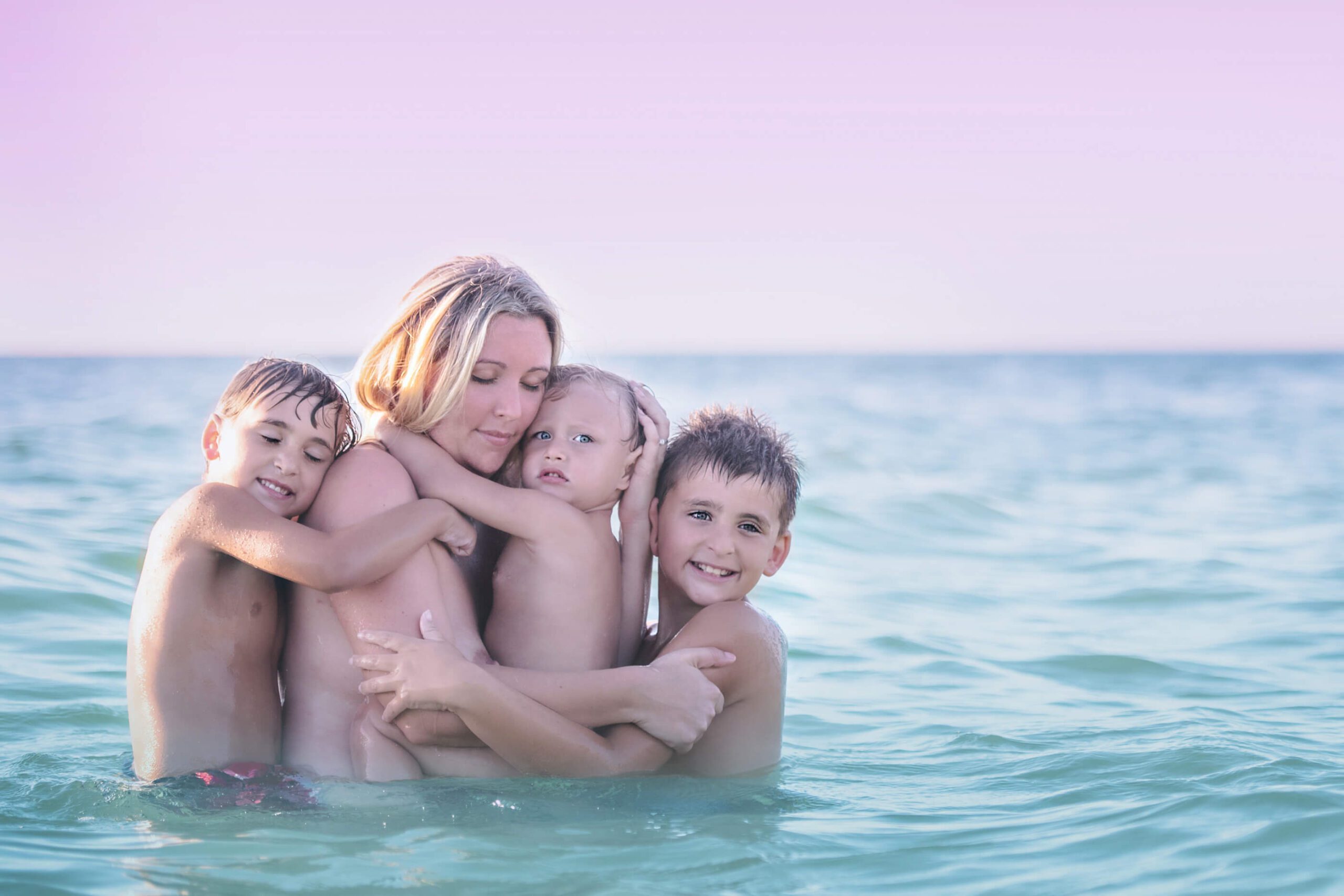 breastfeeding mom in the ocean with her three boys