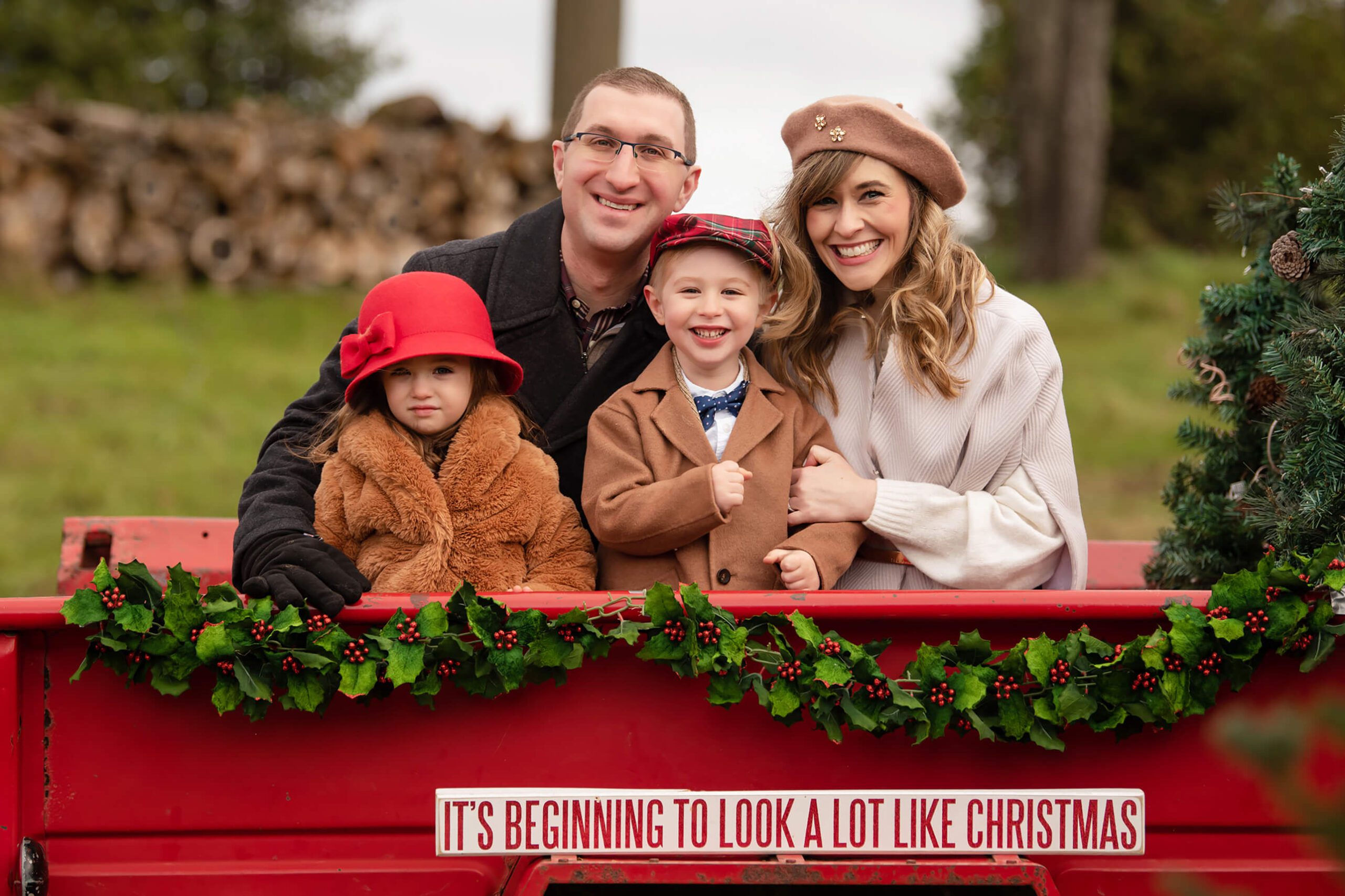 Family of four in a red truck at a tree farm for their family Christmas Photos, WinterFest Canada's Wonderland