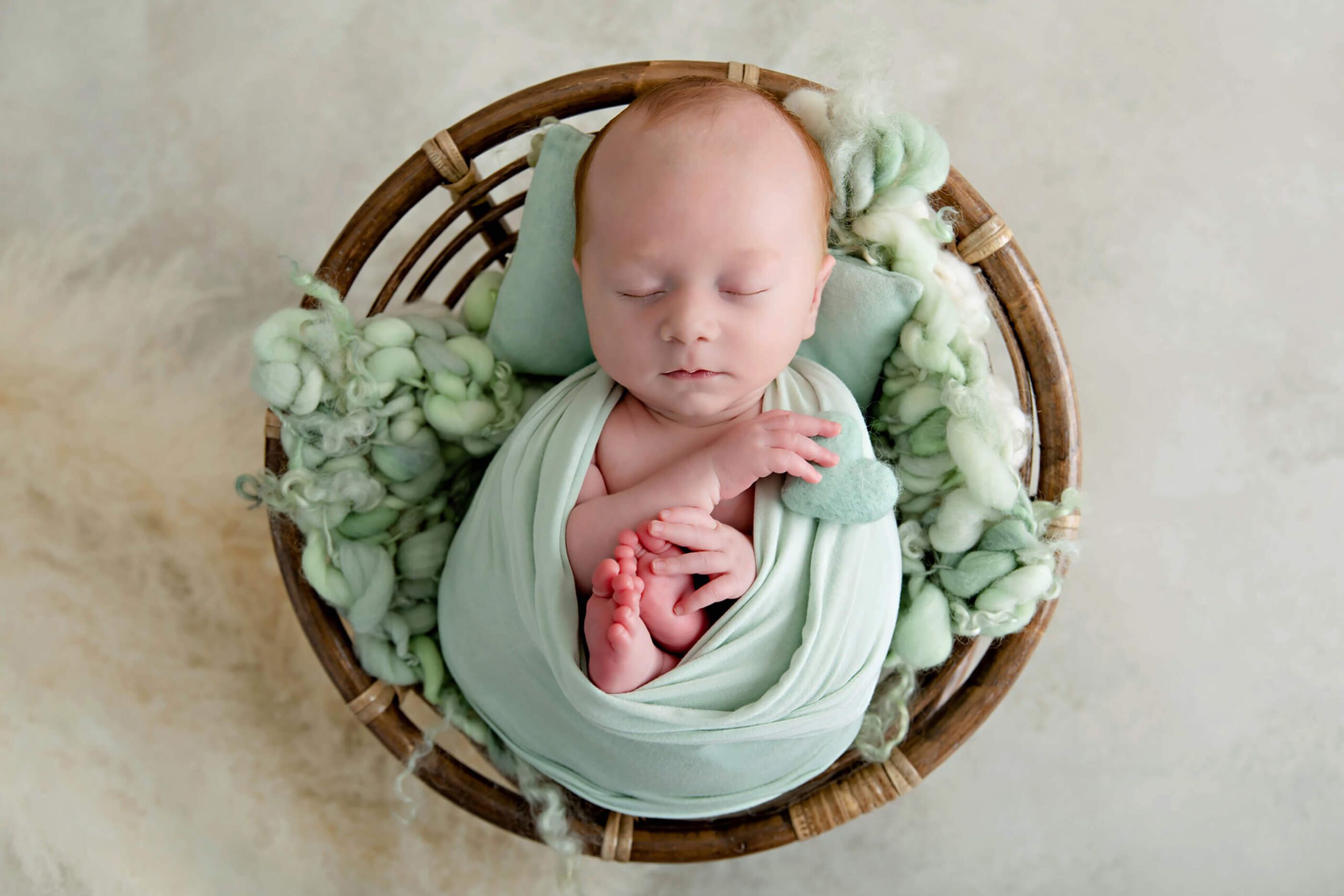 Mint green red-haired newborn boy in a boho Toronto newborn prop