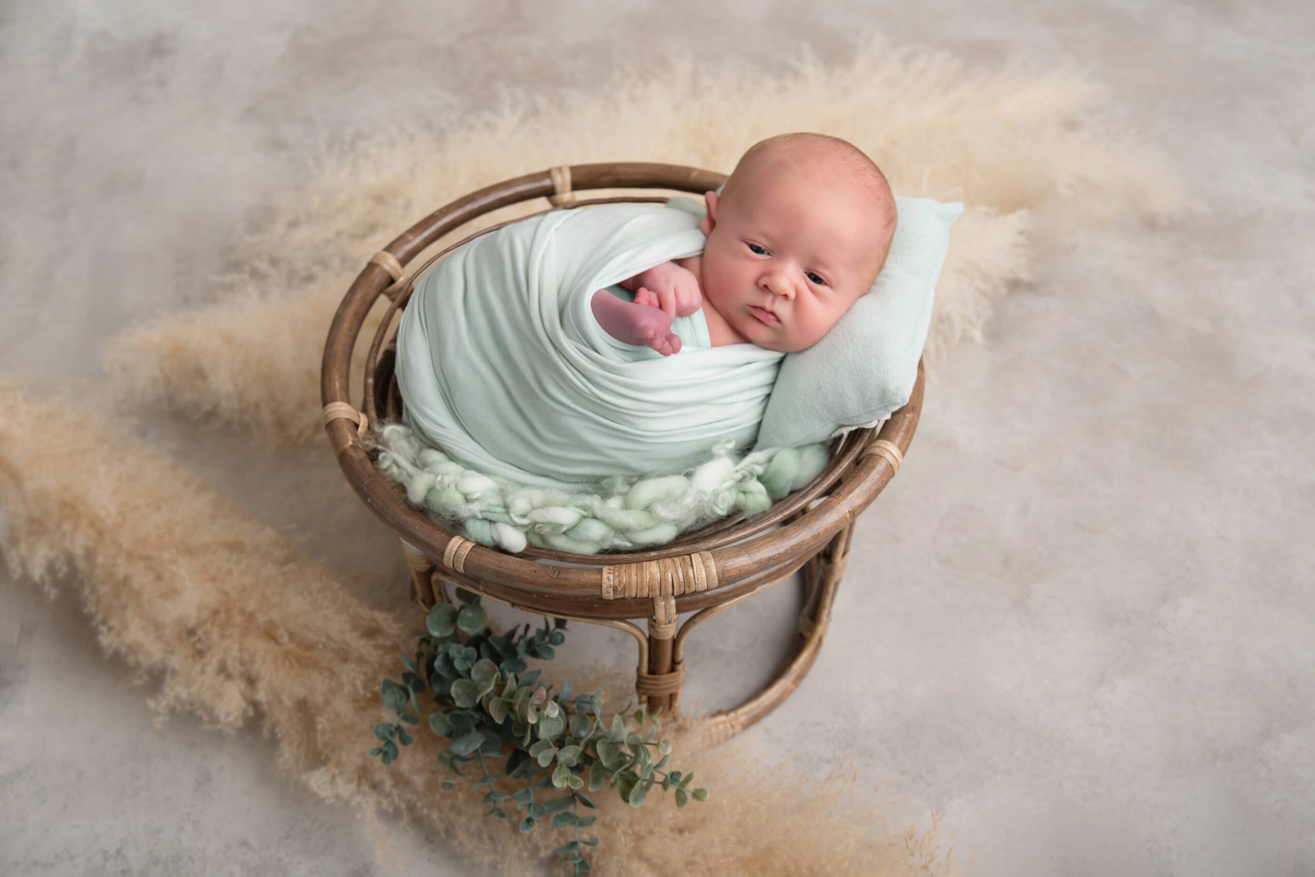 awake newborn baby boy in a wicker bowl boho style Burlington Newborn photographer