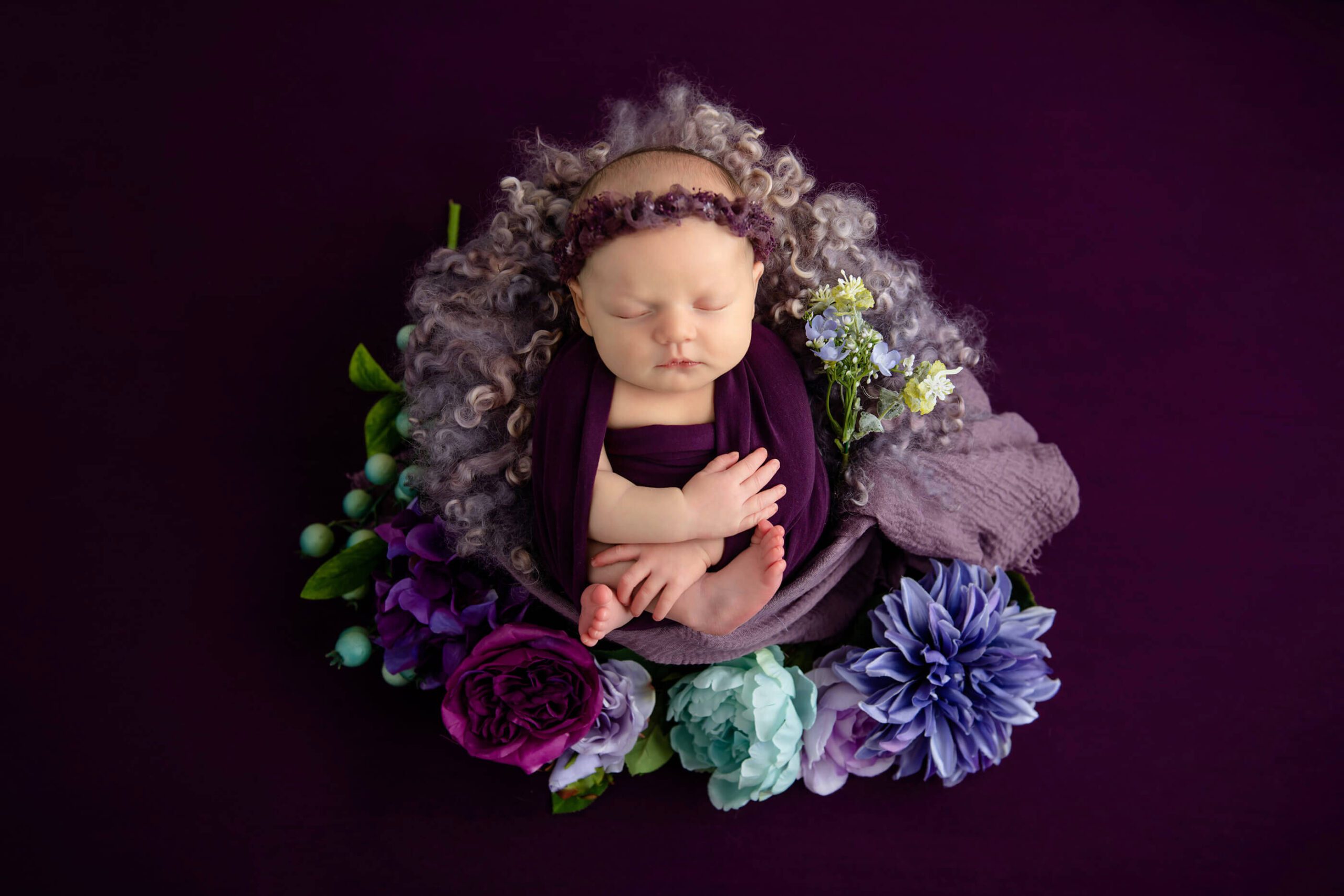 newborn girl with purples and mauve colours with flowers in a bowl