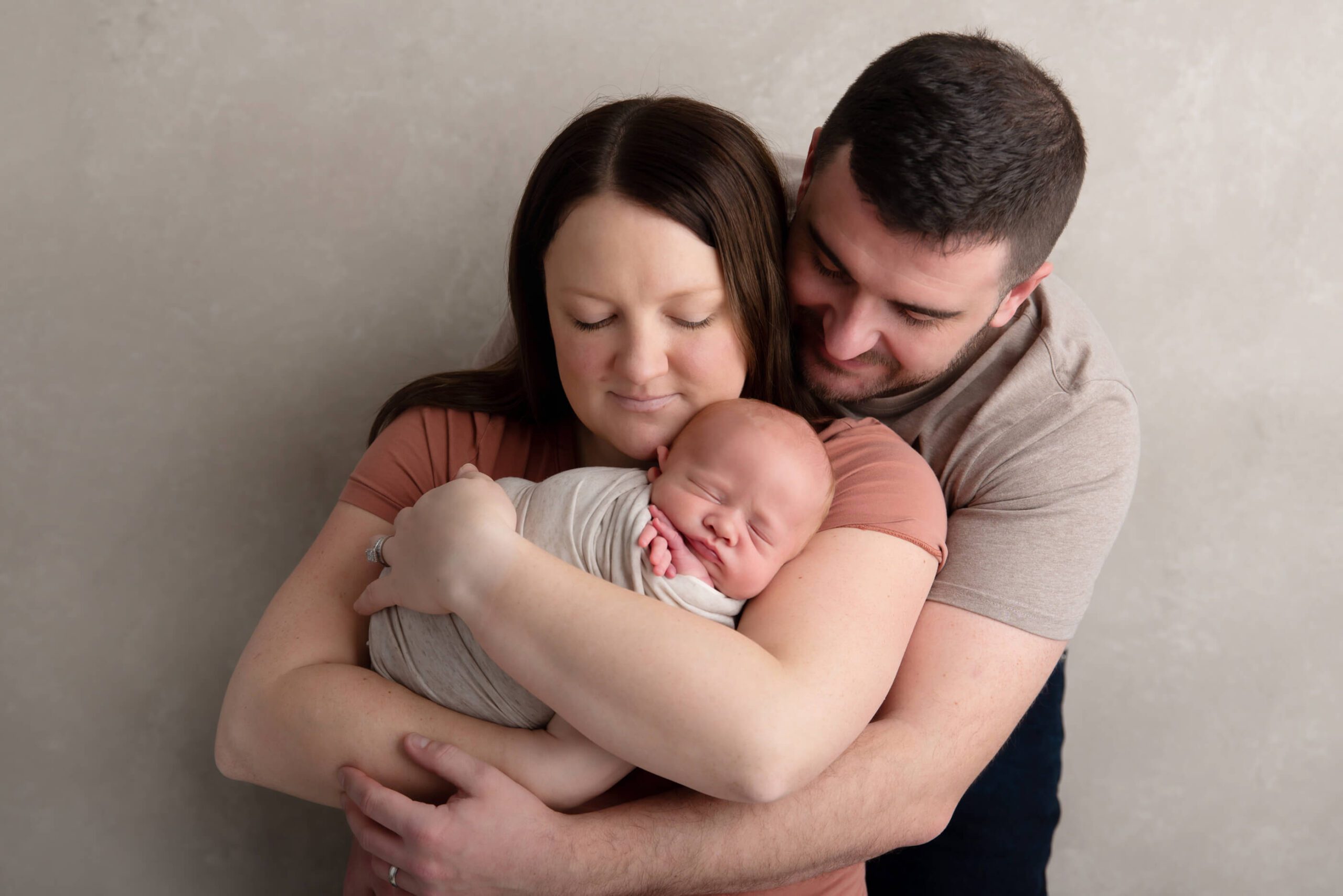 mom and dad looking down at newborn baby boy cuddling Cambridge photographer