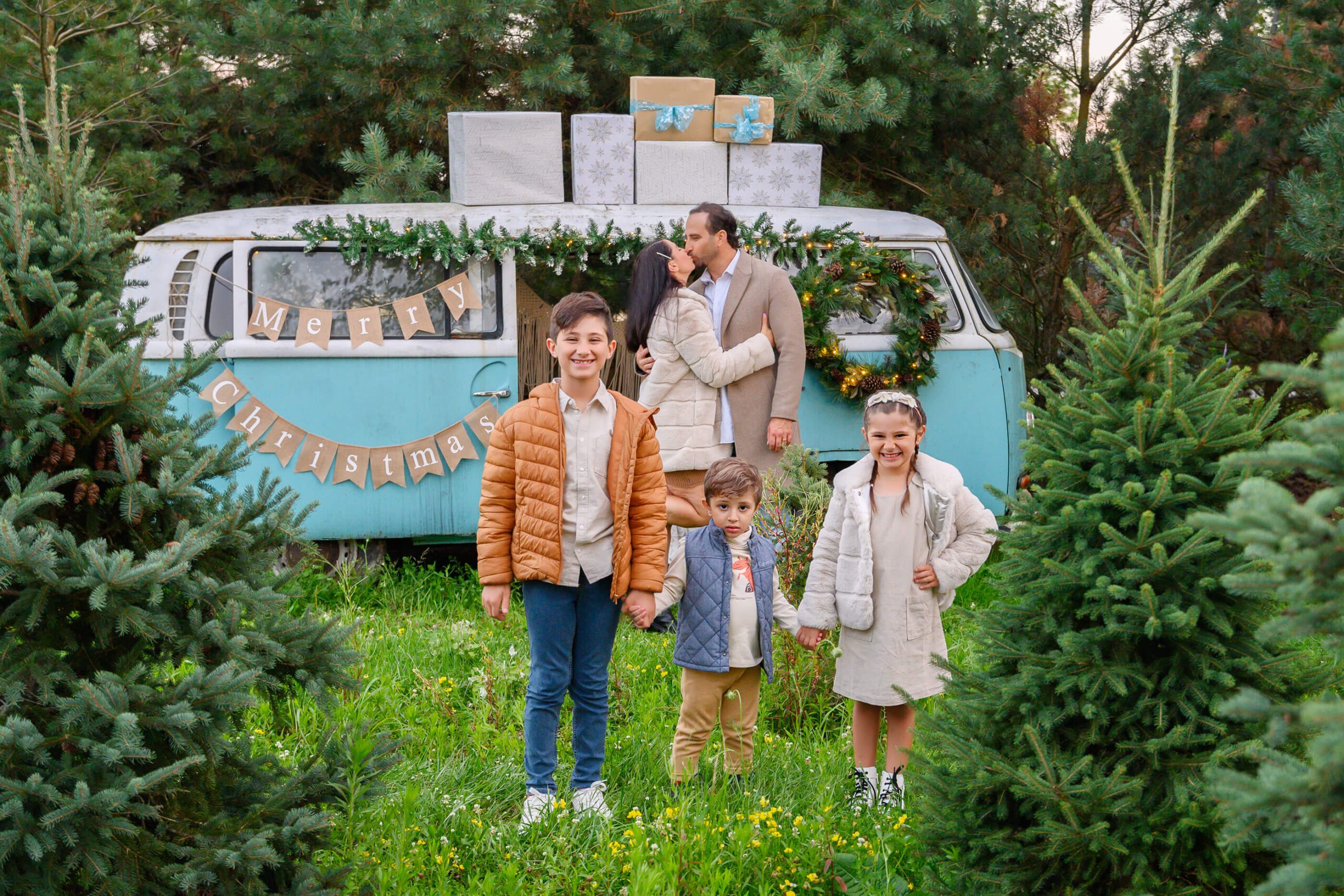 Couple kissing behind their three children with a VW Bus family Christmas Session