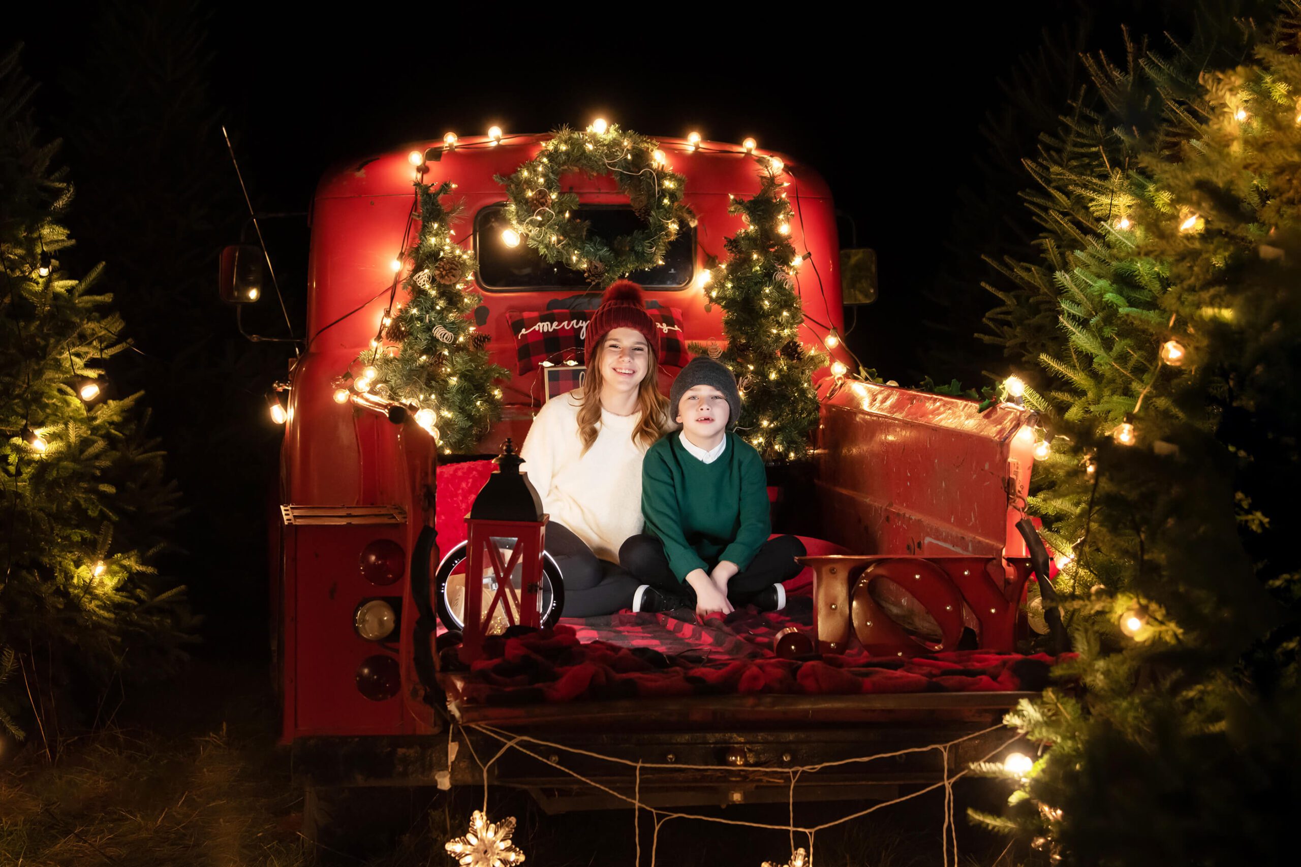 Brother and sister sitting in a red truck Christmas Lights Toronto