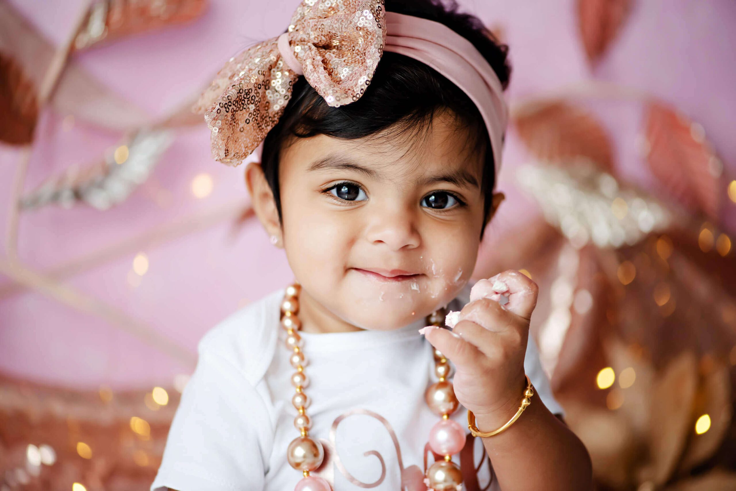 close up of little girl at her rose gold cake smash first birthday photography session