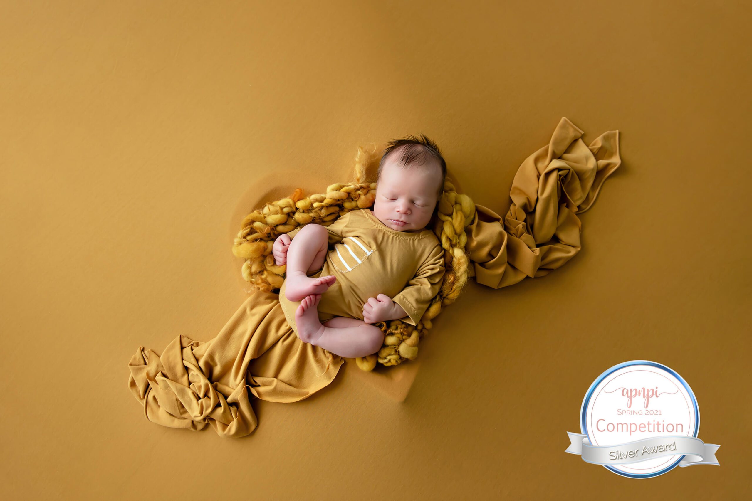 Award-Winning newborn baby photo in all yellow lying in a heart bowl