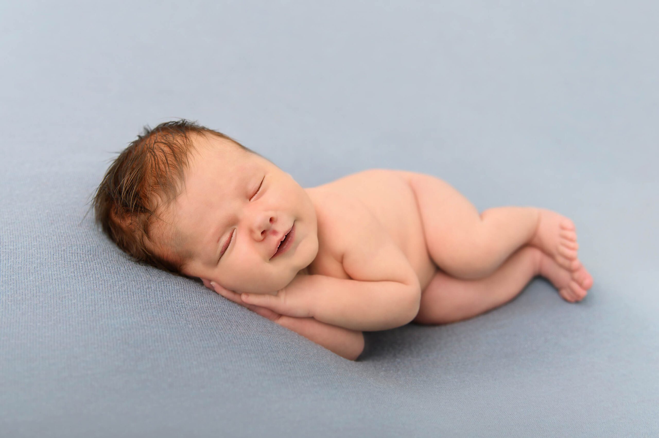 Newborn baby boy smiling, laying on his side Toronto Birth Centre