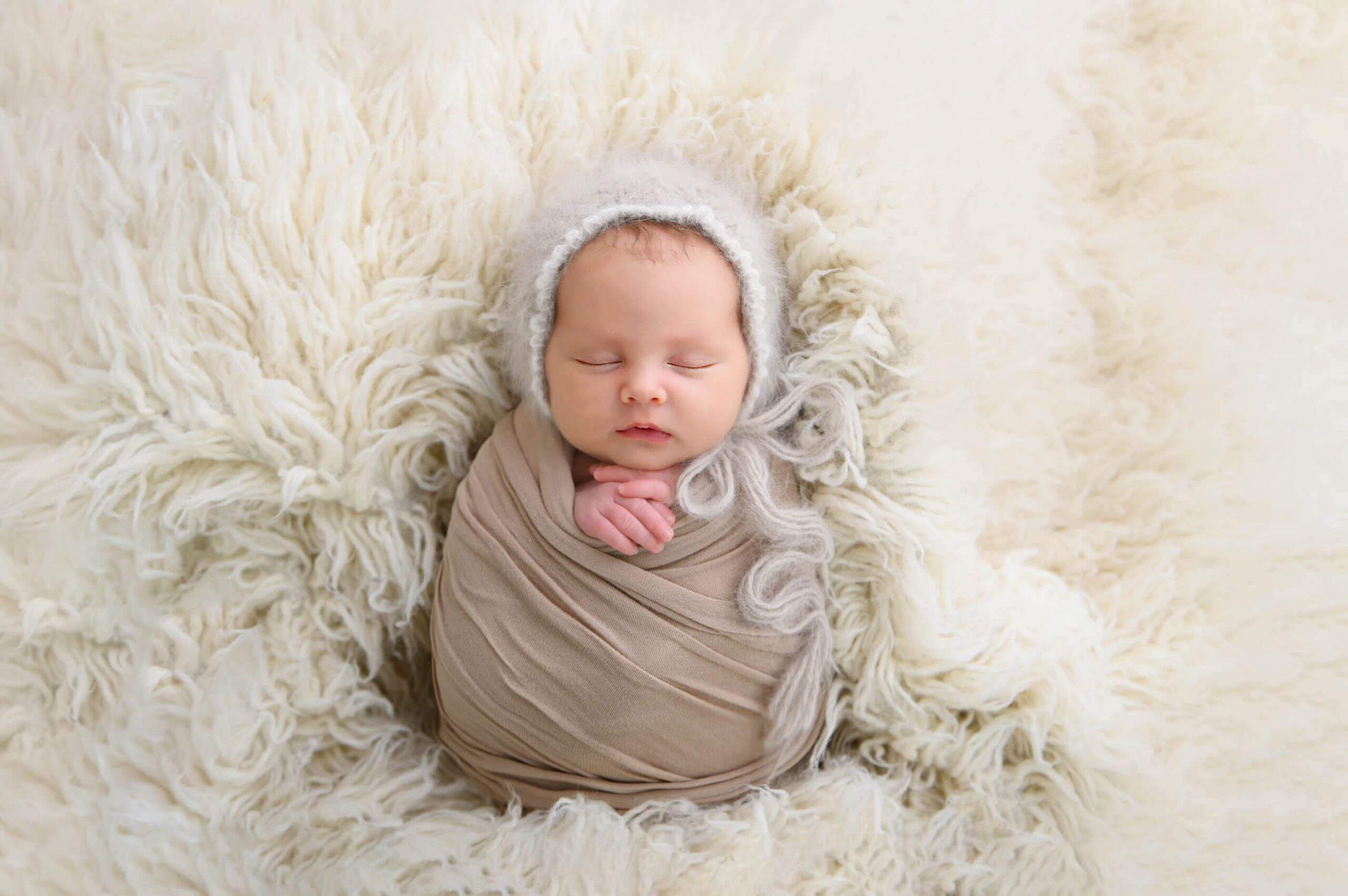 Newborn Photographer Toronto Birth Centre baby girl wrapped in beige laying on a fluffy cream rug