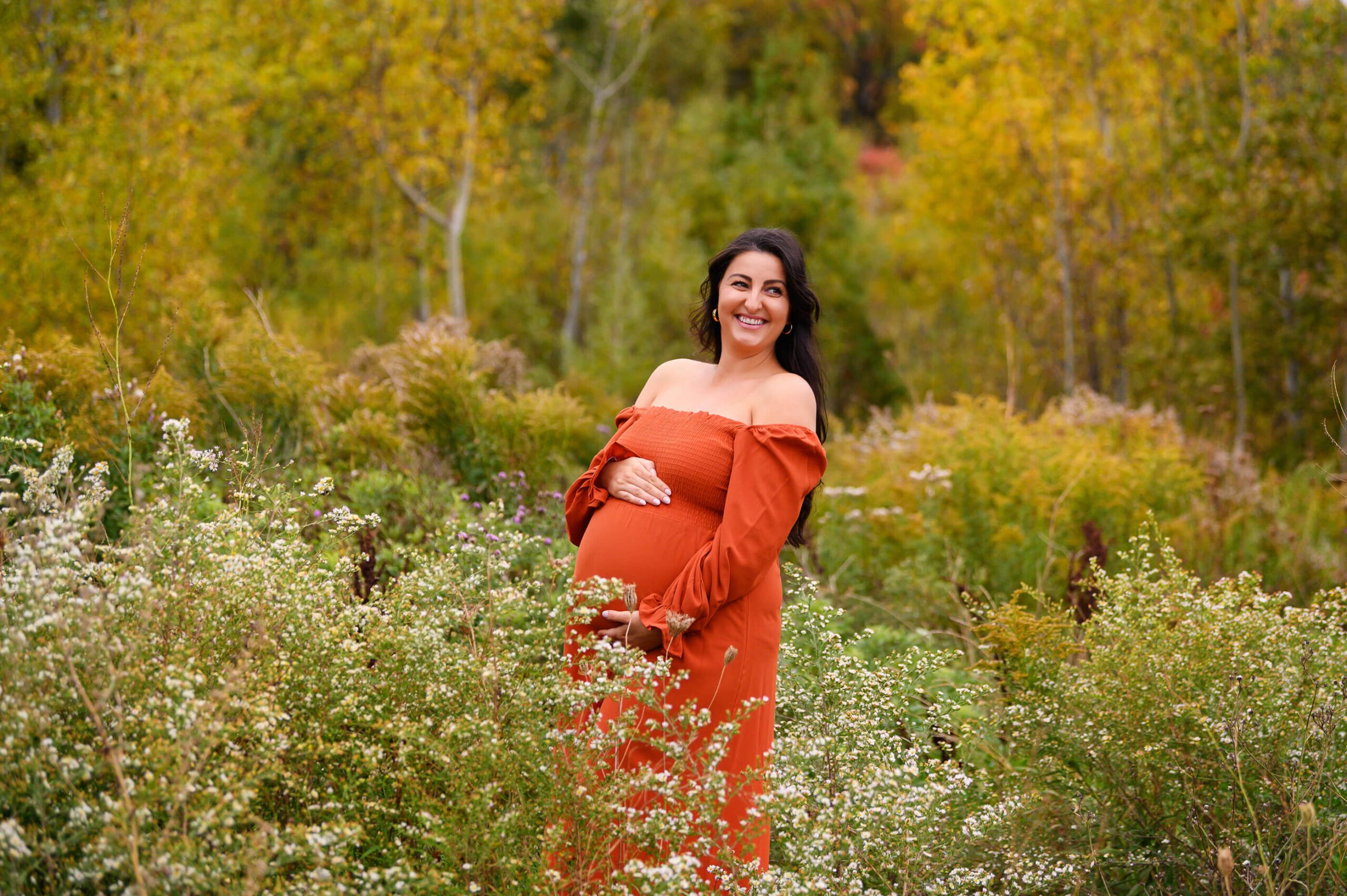 Mom to be holding her baby belly wearing an orange dress. Toronto Pelvic Floor Physiotherapy 