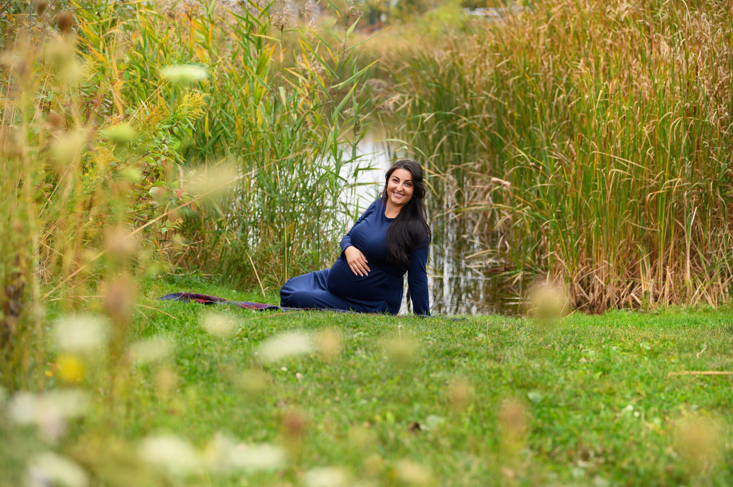 Mom sitting wearing an blue dress holding her belly