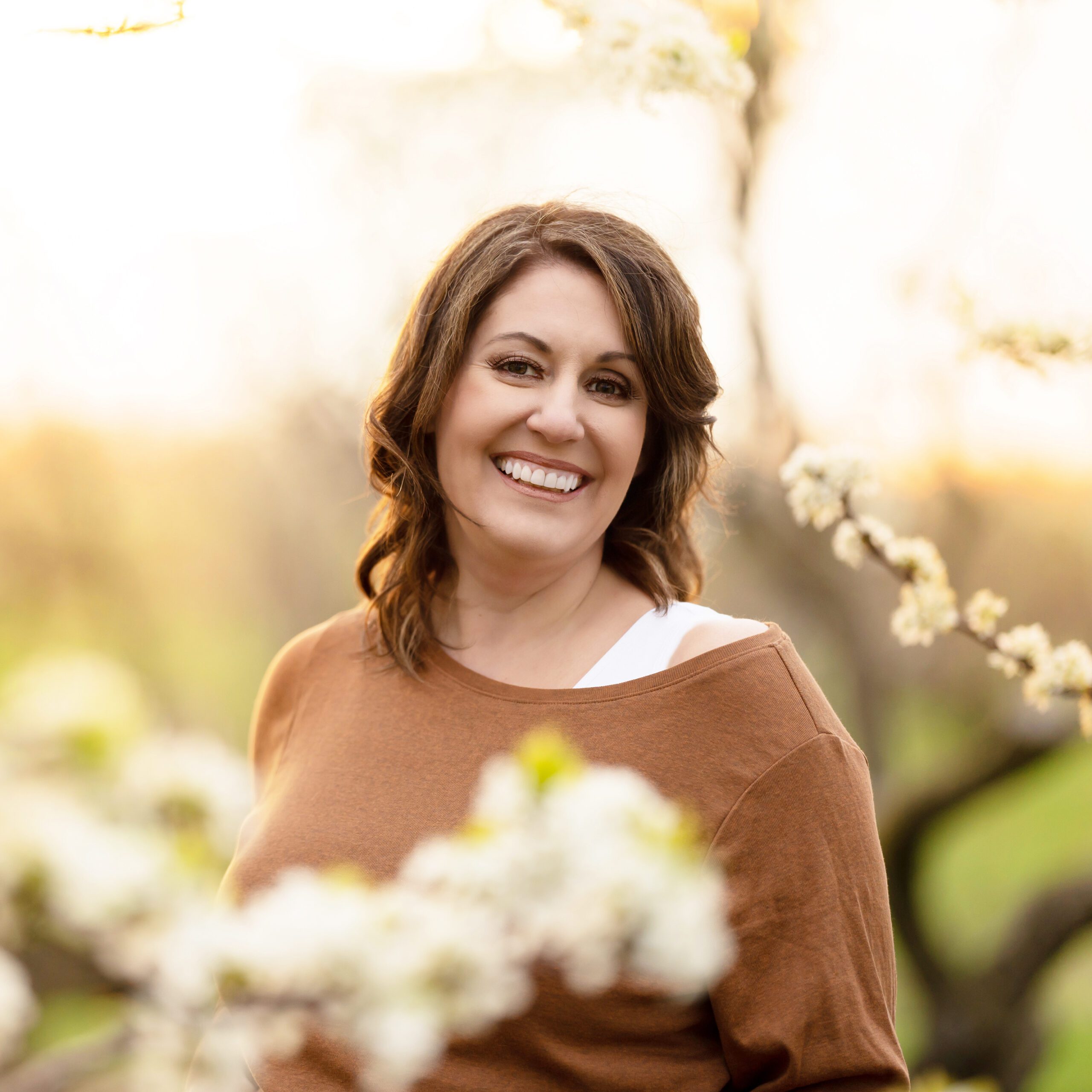 Amanda Gibson Toronto Newborn Photographer in gold shirt in the Cherry Blossoms Smiling.
