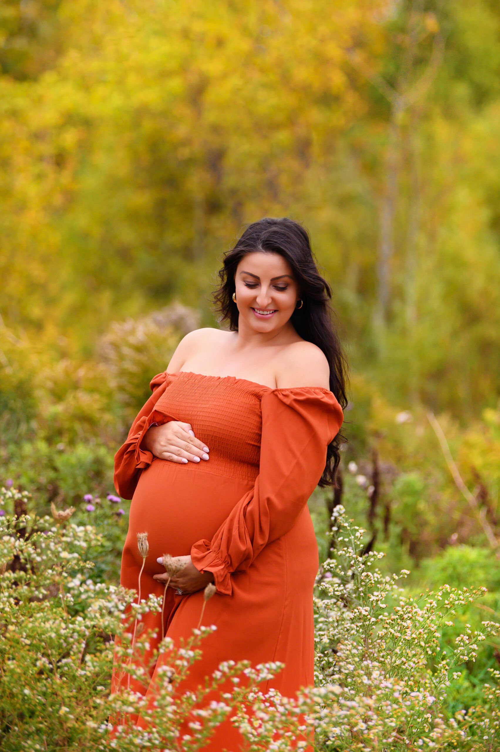 Mom in orange dress in the fall foilage outdoor maternity session