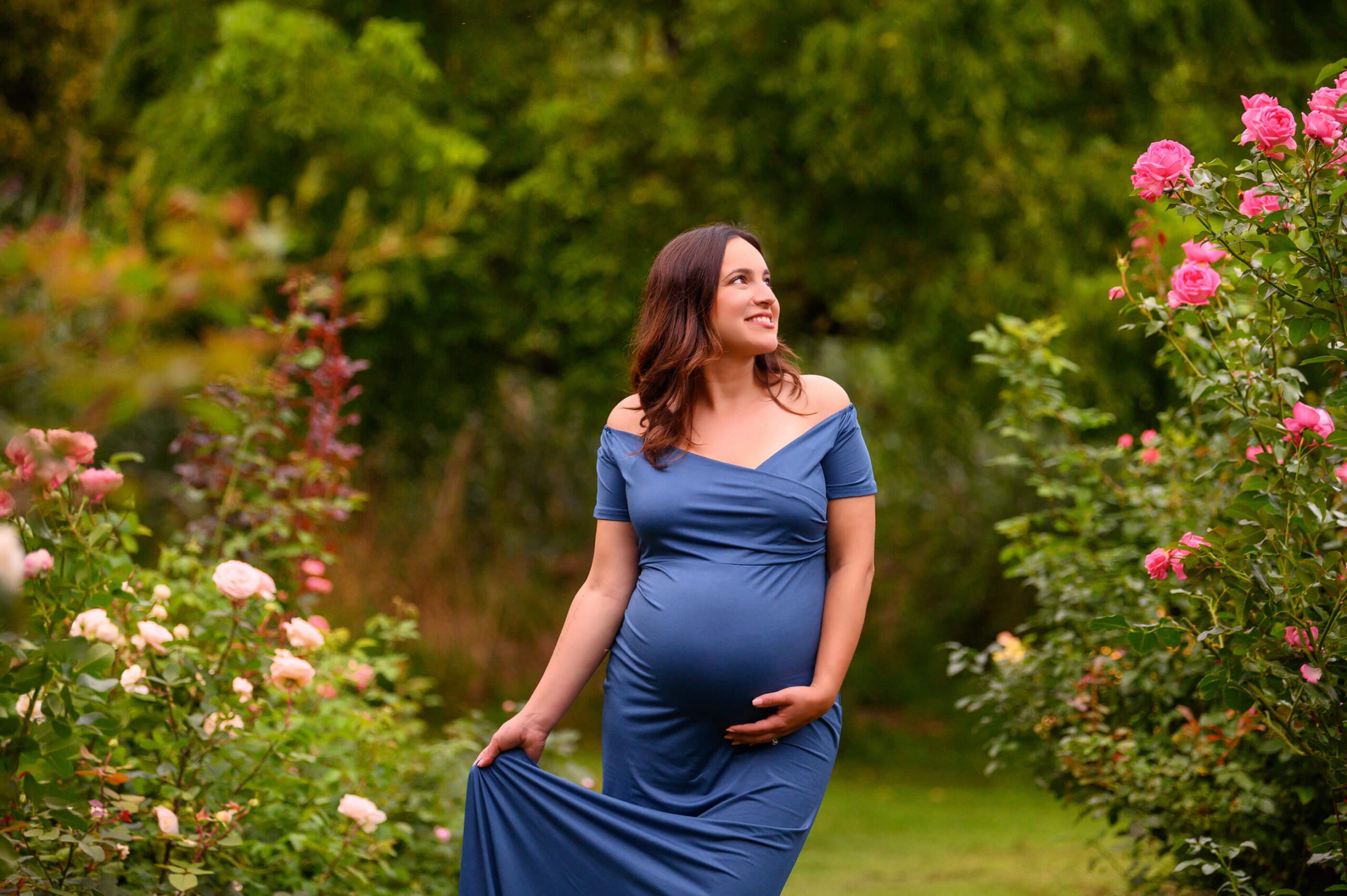 Burlington, Ontario Maternity Photographer mom in a blue dress holding her belly and smiling