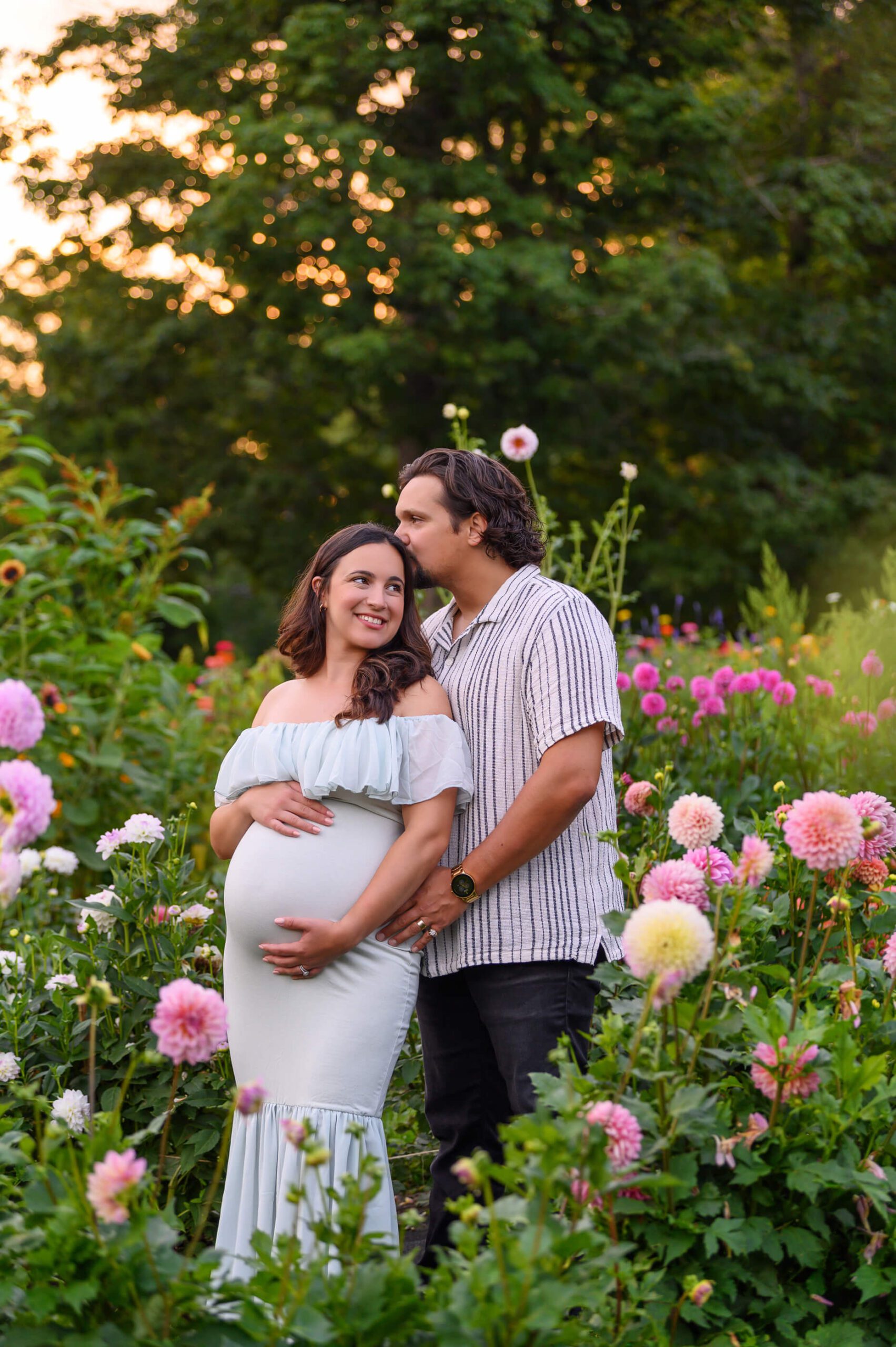 husband kissing wife on the head maternity photography session in the flower field
