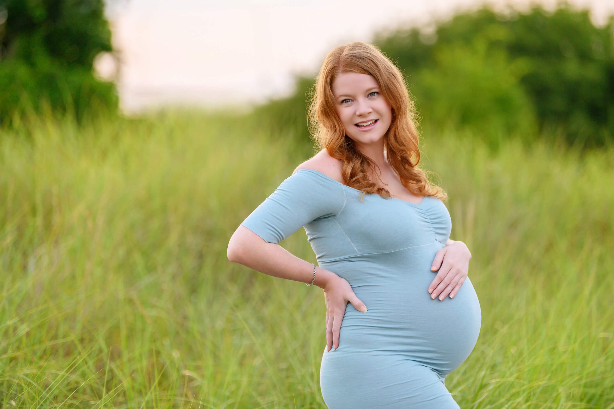 Red haired mom holding her belly in the golden hour for her Toronto Maternity Photography