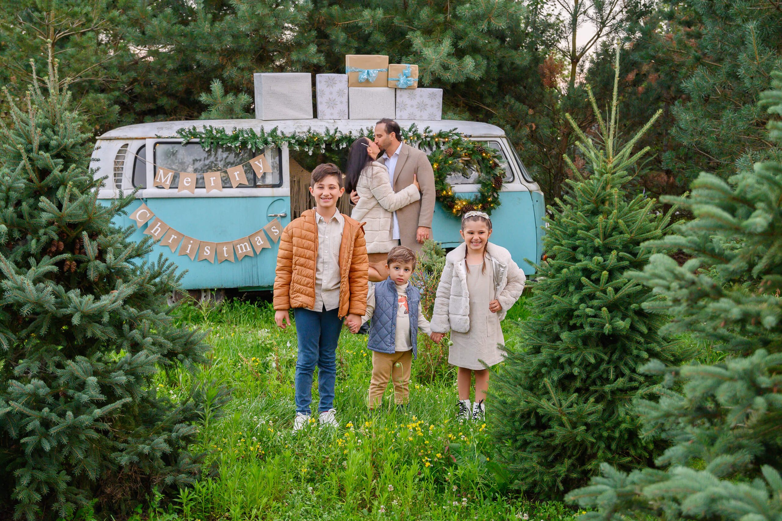 VW Bus Family Christmas Photos mom and dad kissing with three children two boys and a girl.