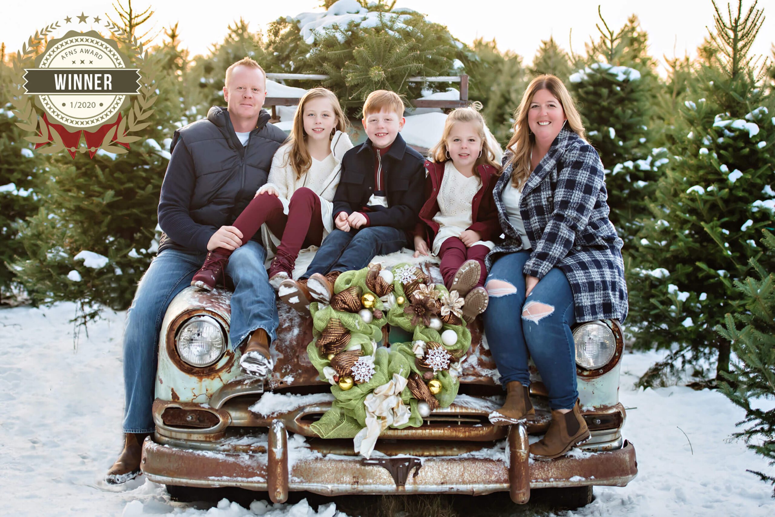 Award-winning Christmas Family photos family of five sitting on a green station wagon at the Christmas Tree Farm.