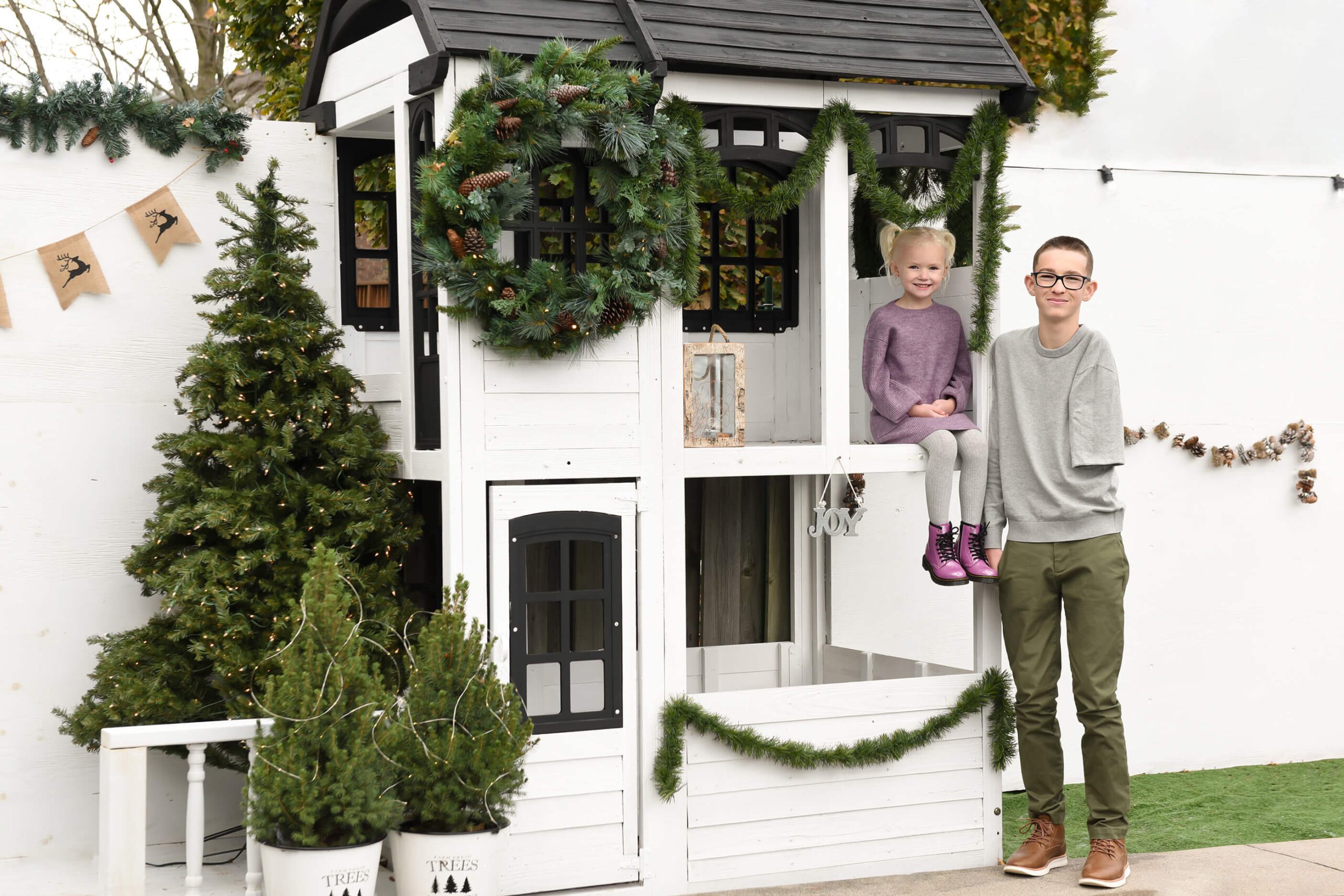 Brother and sister sitting in a white three-house for their Hamilton Christmas Lights family photos.