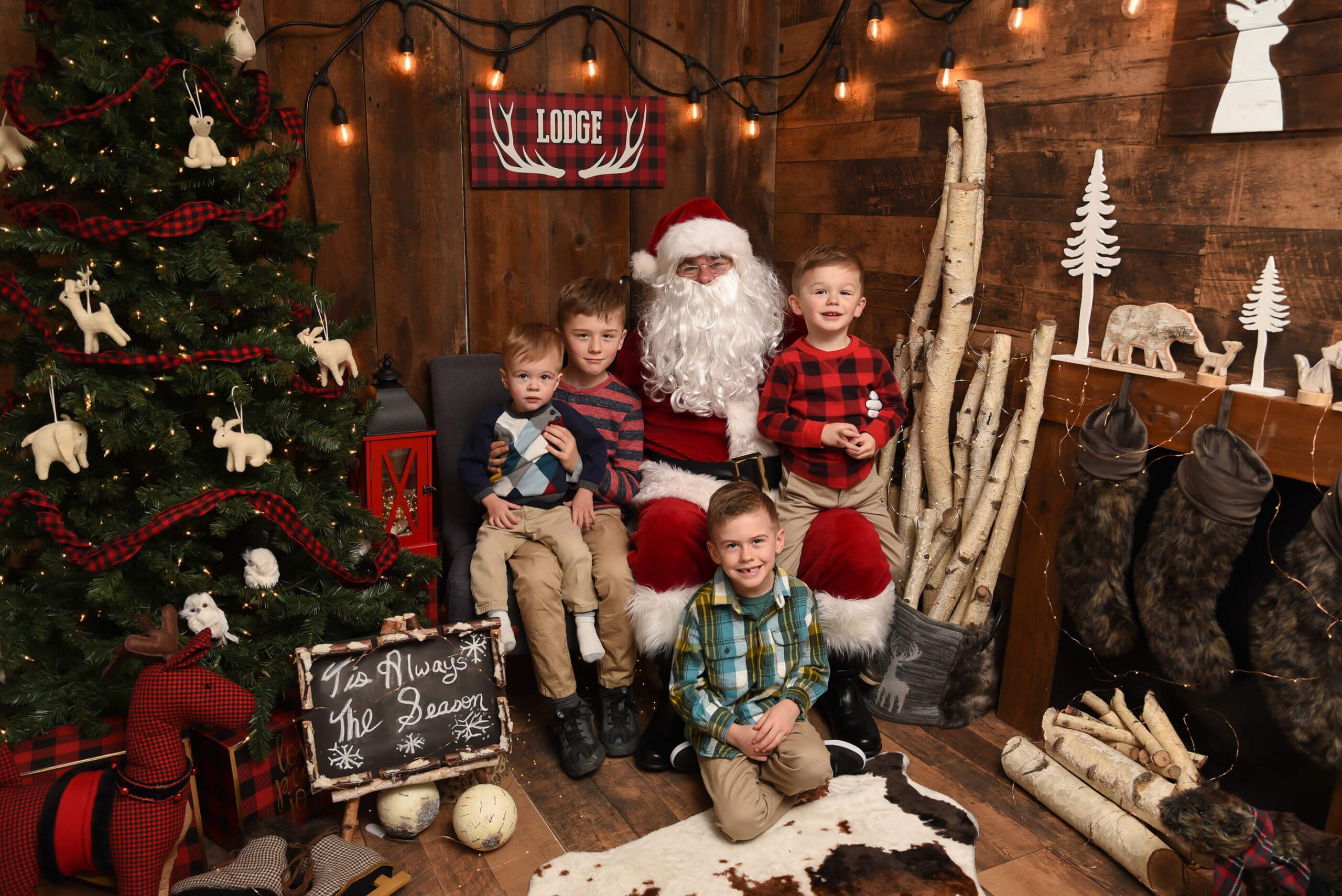 Four boys sitting with Santa in a dark wood lodge setting