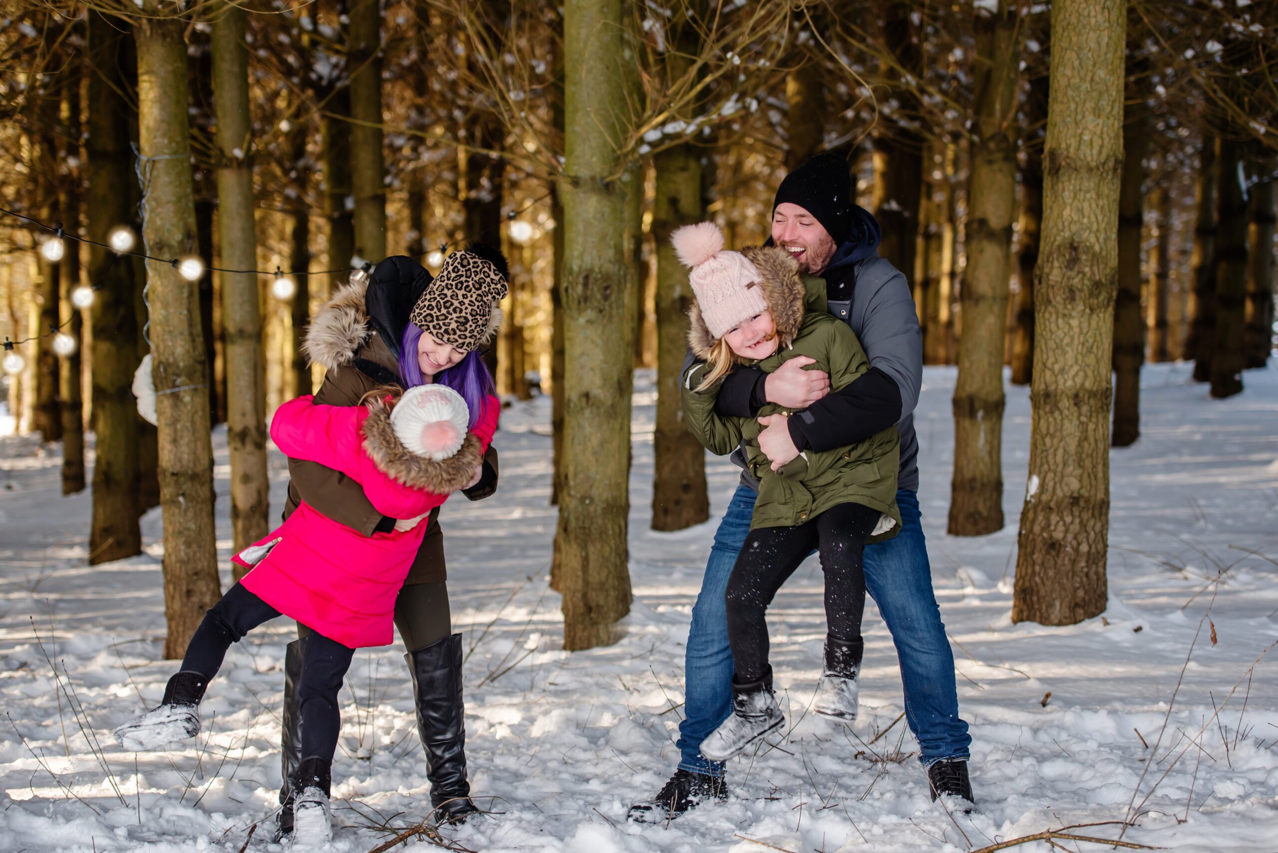 mom and dad playing with their two daughters in the snow in a winter activities Toronto 