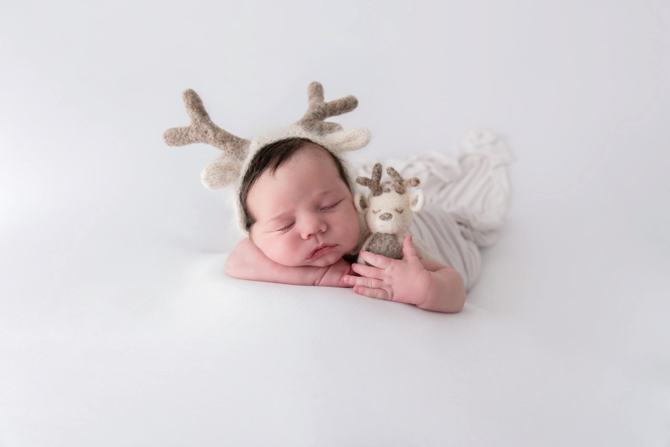 baby girl in a reindeer hat holding a tiny reindeer Burlington, Ontario newborn photographer