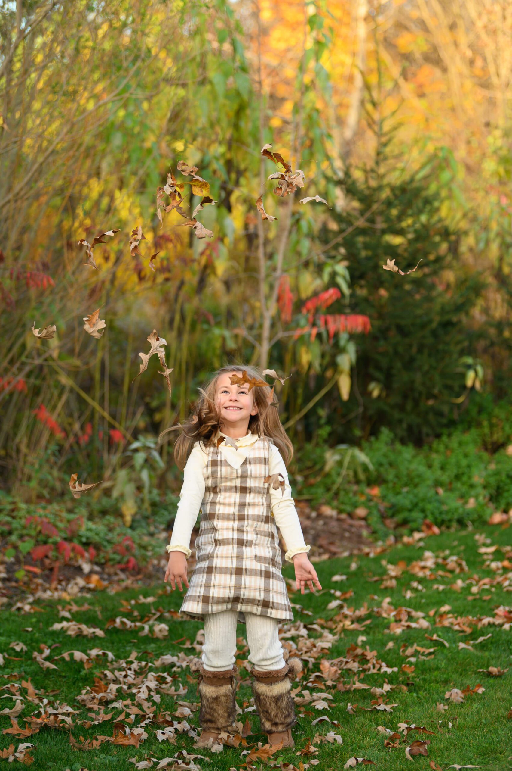 little girl throwing leaves in the air.