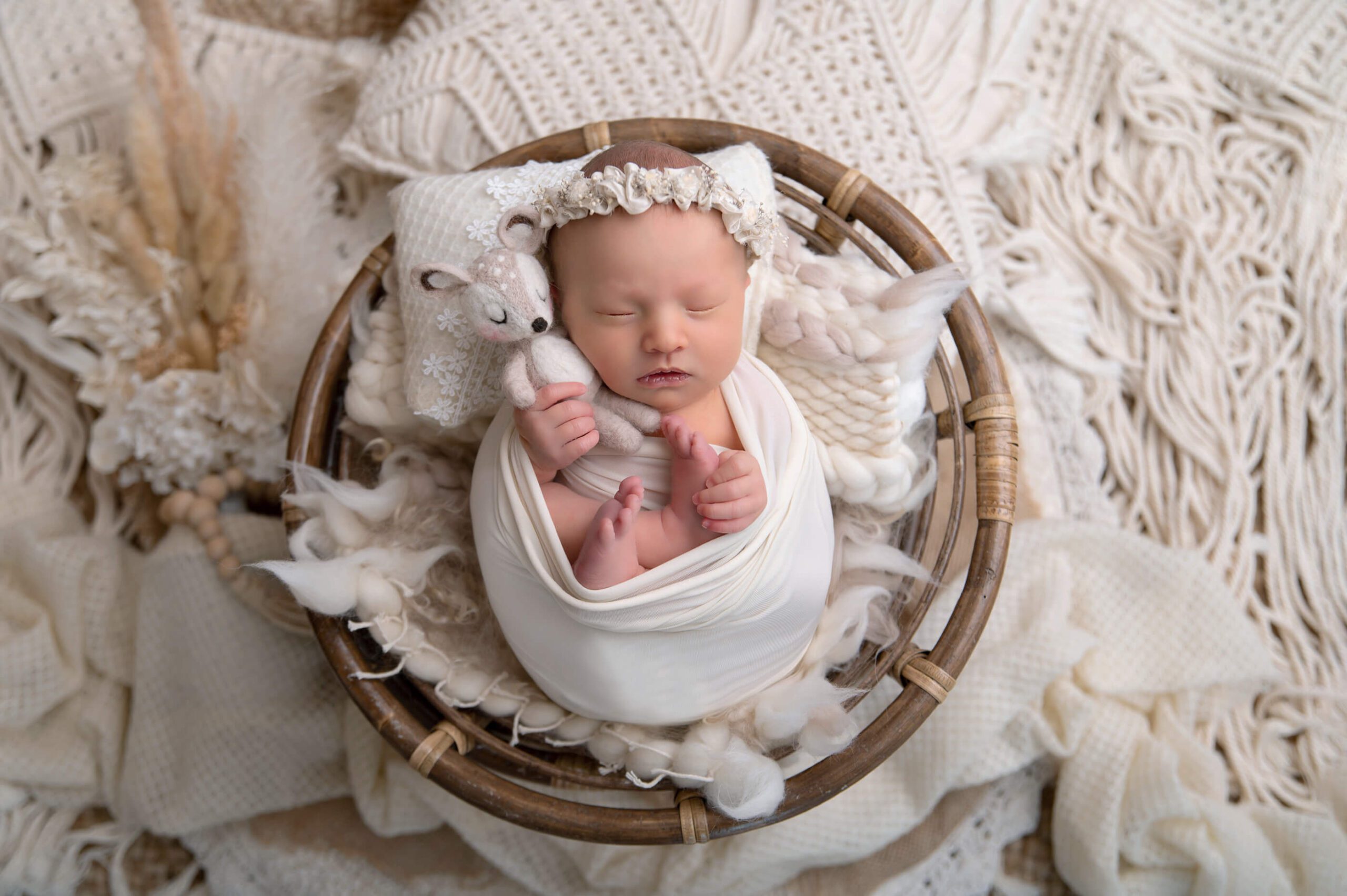 newborn baby girl holding a fawn laying in a round bowl. Burlington, Ontario photographer