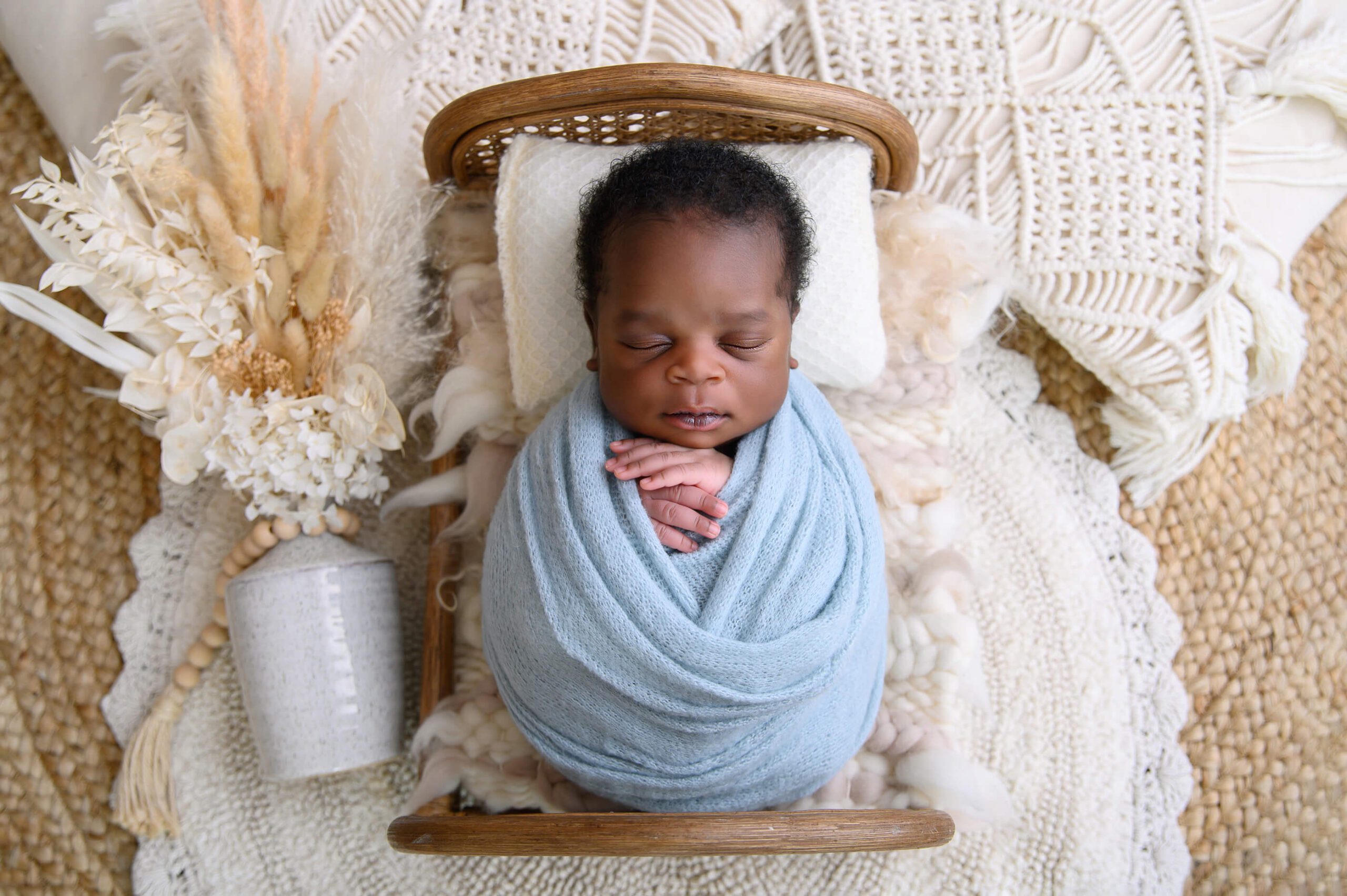 newborn baby boy wrapped in blue laying on a little bed for his Toronto Newborn Photography session.