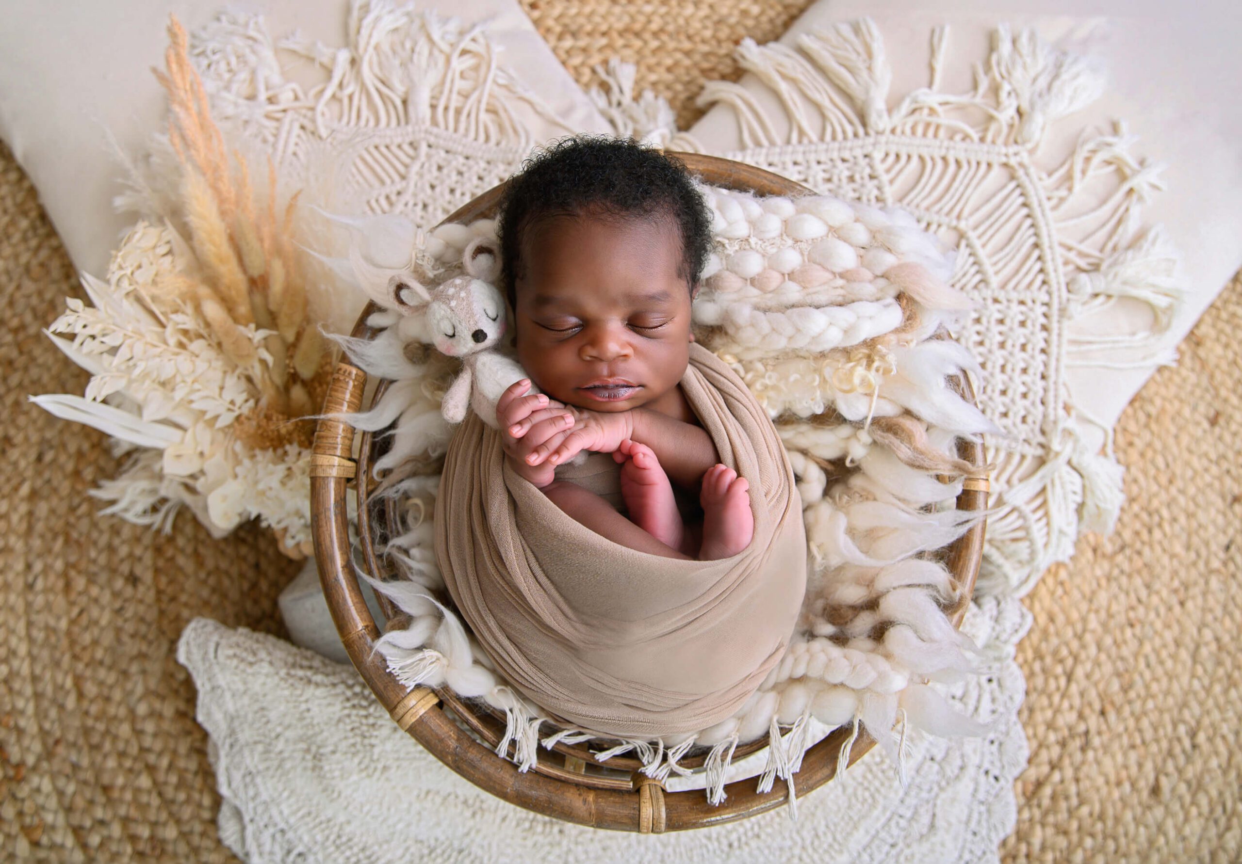 Boho newborn photography session baby boy holding a little fawn.