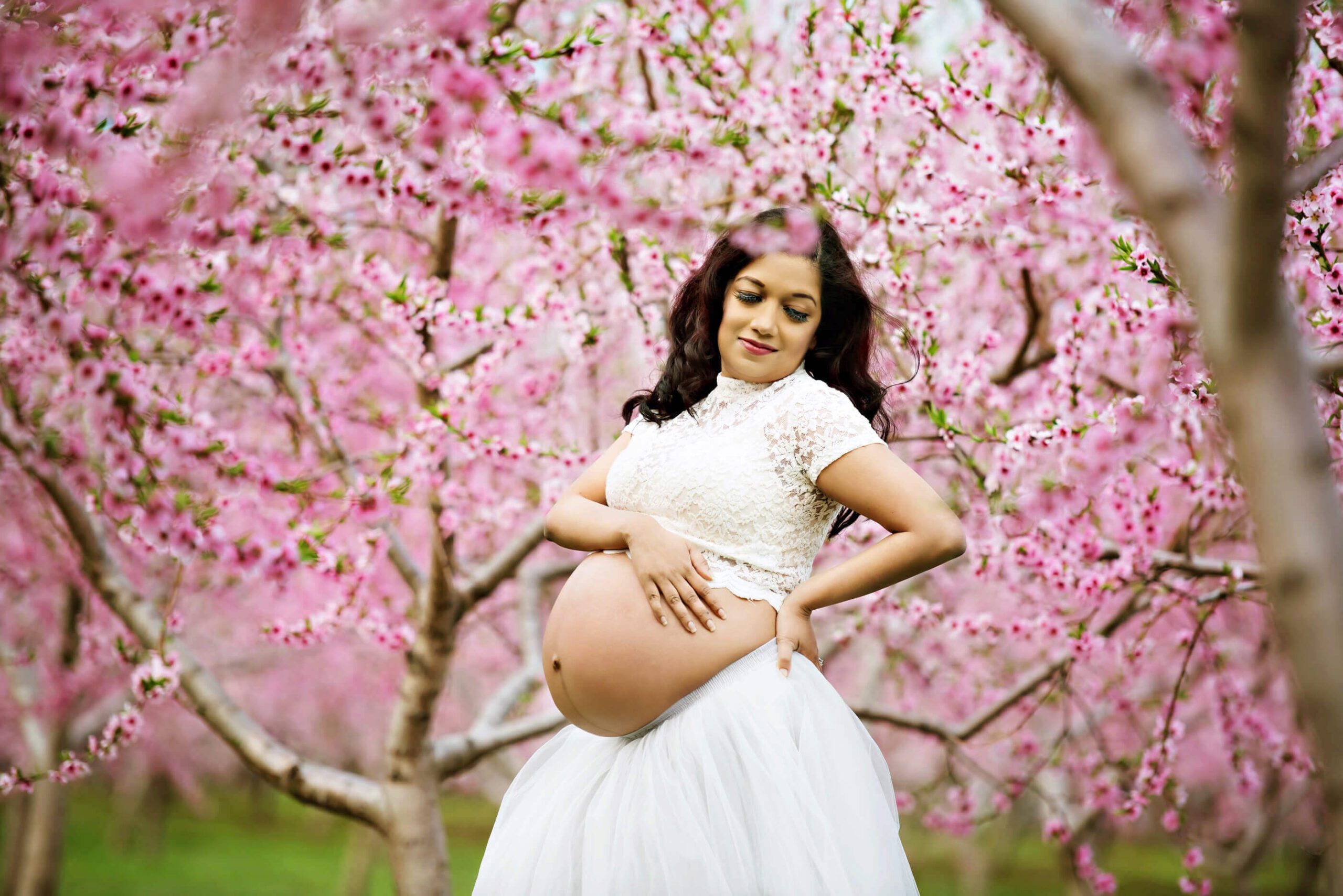 Pregnant woman wearing a lace white crop top and grey tutu for her maternity photography session.