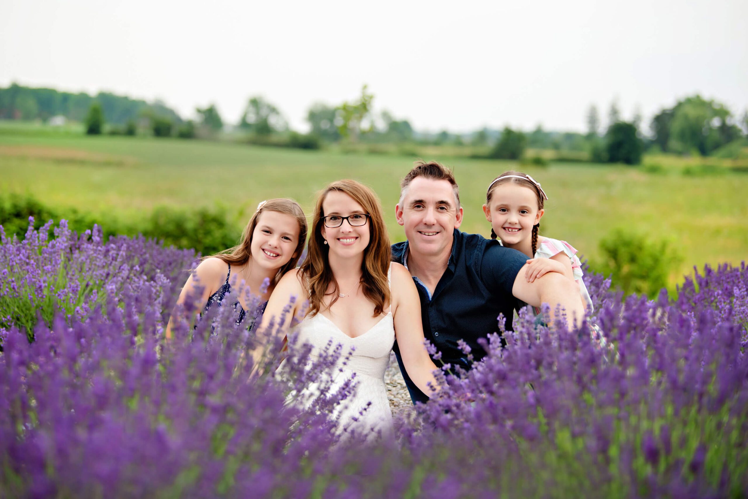 family of four with two daughters sitting in the lavender fields